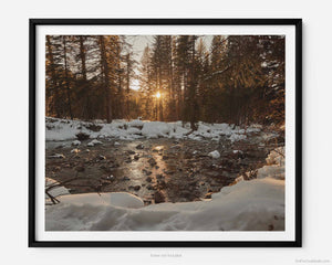 This fine art photography print shows winter in Vail, Colorado at Vail Ski Resort. As sunset peers thru the pines, you see snow pillowed on rocks amidst a peaceful serene waterway of Gore Creek.
