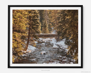 This fine art photography print shows winter in Vail, Colorado at Vail Ski Resort. As the sunsets, a rustic wood bridge spans across the peaceful waterways of Gore Creek.