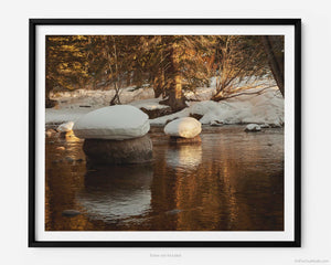 This fine art photography print shows winter in Vail, Colorado at Vail Ski Resort. As sunset peers thru the pines, you see snow pillowed on rocks amidst a peaceful serene waterway of Gore Creek.
