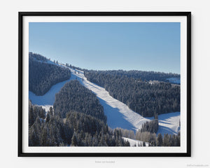 This fine art photography print shows winter in Vail, Colorado at Vail Ski Resort. The air is crisp and cool looking off towards the Game Creek ski trails on the back side of the mountain. Flanked by the clear blue skies, snow-capped Rocky Mountains, and pine trees, there are stunning views of runs like Showboat, Wild Card, and Deuces Wild.