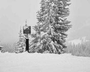 This black and white fine art photography print shows winter in Vail, Colorado at Vail Ski Resort. Capturing the thrill of the slopes, this print showcases a sign reading "extreme terrain" at the top of an expert black diamond ski run on a snowy day with near white out conditions.