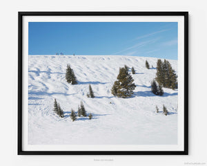 This fine art photography print shows winter in Vail, Colorado at Vail Ski Resort. The air is crisp, and cool as you look off towards the Wildwood Express ski lift, taking in a stunning view of skiers at the top of Kangaroo Cornice's black diamond skin run. 