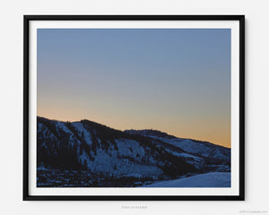 This fine art photography print depicts the serene beauty of winter at Bachelor Gulch in Avon, Colorado with a sunset cresting peacefully over snow-covered mountains.