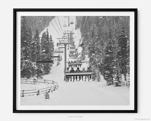 This black and white fine art photography print shows the iconic Avanti Express ski lift at Vail Ski Resort in Vail, Colorado. The piece captures the excitement of skiers as they make their way up the snowy mountain.