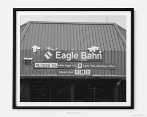 This black and white fine art photography print shows winter in Vail, Colorado at Vail Ski Resort. The iconic Eagle Bahn Gondola, covered in some light snow, lists access to Little Edge #15, Game Trail, Adventure Ridge, and Eagle’s Nest. 