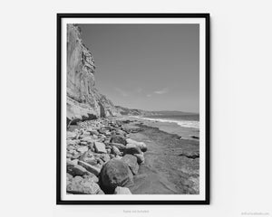 This black and white fine art photography print shows the natural rock formations facing the Pacific Ocean from Black's Beach at Torrey Pines National Reserve in San Diego, California. Miles of pristine beach stretch out into the distance. 