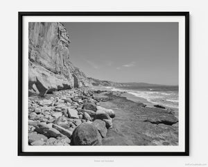 This black and white fine art photography print shows the natural rock formations facing the Pacific Ocean from Black's Beach at Torrey Pines National Reserve in San Diego, California. Miles of pristine beach stretch out into the distance. 